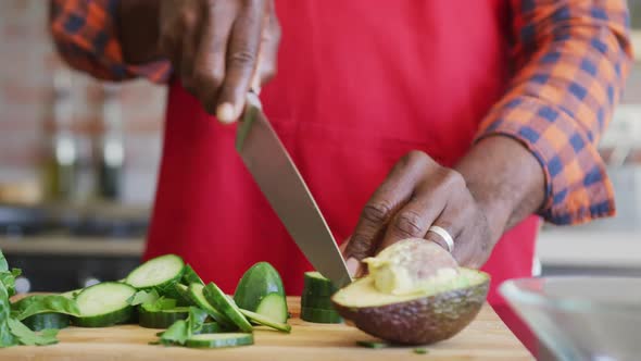 Hands of african american senior man cutting vegetables