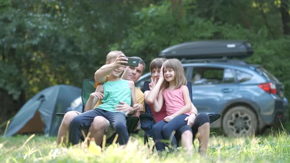 Happy Family Sitting Together at Campsite and Taking Selfie with Mobile Phone