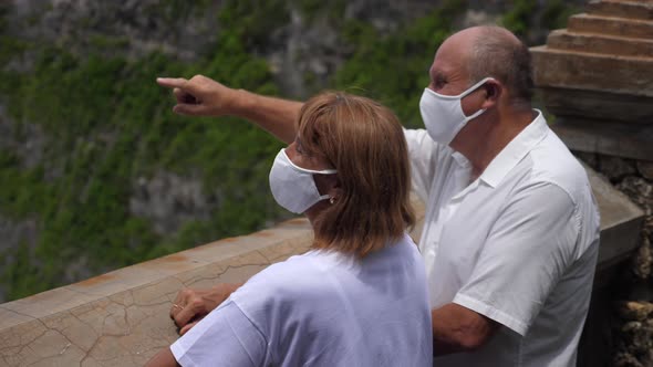Senior Couple in Protective Face Masks Enjoying the Breathtaking View of the Ocean From an