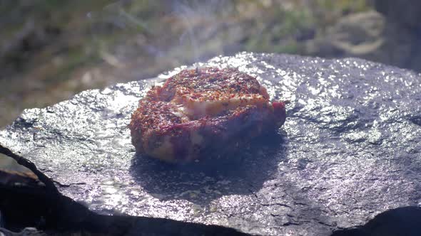 Junk Food, Succulent Fatty Pork Filet in Spice Fried on Hot Stone at Bonfire with Smoke in Campsite