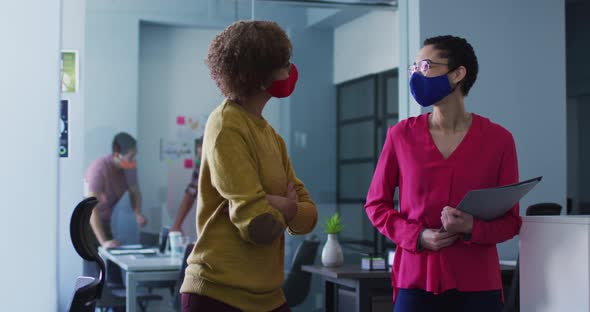 Mixed race female colleagues wearing face masks in office