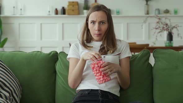 Woman Watching a Horror Movie and Eating Popcorn