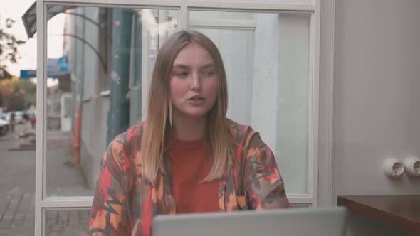 Portrait of Beautiful Girl in Cafe Talking on Video Through Laptop Webcam.