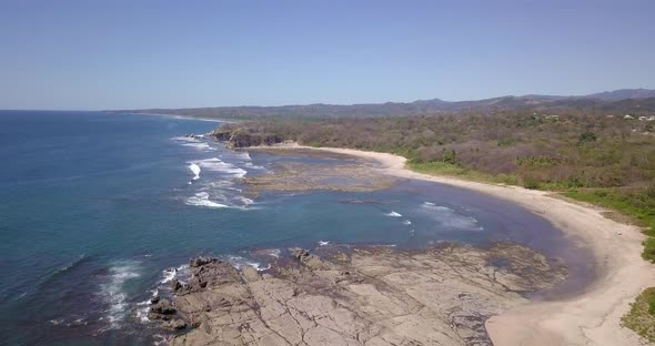 Aerial drone view of the beach, rocks and tide pools in Playa Palada, Guiones, Nosara, Costa Rica