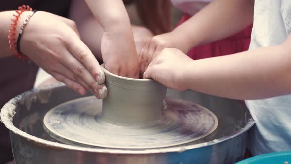 Grandmother with a Grandchildren Make Pitchers in Pottery