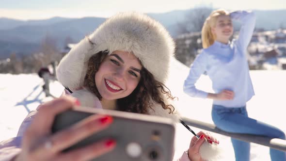 Girls Friends Making Mobile Photo at Snowy Mountain Landscape