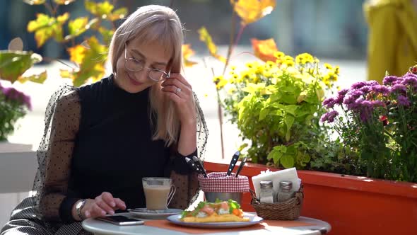 Breakfast in Cafeteria, Young Woman Is Sitting at Table on Street Terrace at Sunny Autumn Morning