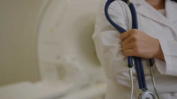 A Stethoscope in the Hands of an Unrecognizable Nurse on the Background of an MRI