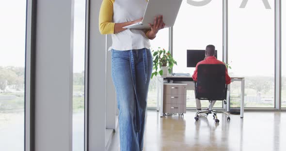 African american creative businesswoman standing with laptop in modern interiors