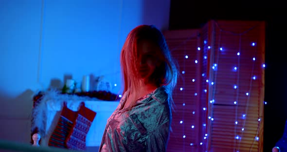 a Blonde in Pajamas Is Kneeling on the Bed. She Turns and Smiles. the Camera Moves From the Bottom