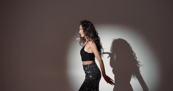 Young Woman with Curly Hair Dancing in a Dark Studio