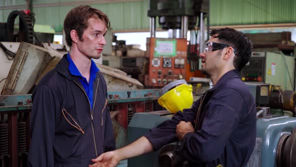 Tired Factory Workers Taking a Break and Talking to Coworker in the Factory