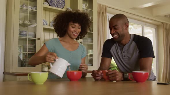 Happy mixed race couple eating breakfast in their kitchen