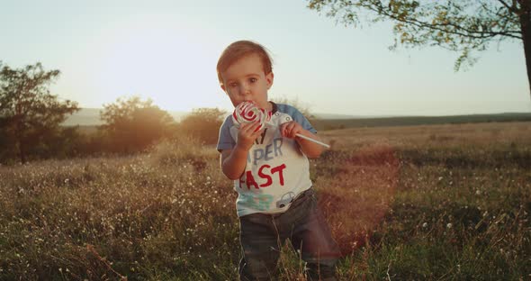 At Sunset Baby Boy Eating a Lollipop, Falling Down