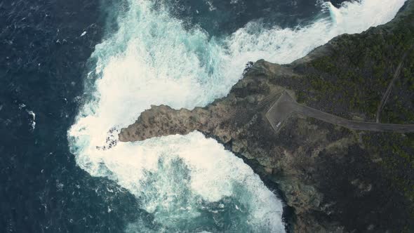 Aerial view of the crispy waves breaking on the rocks.