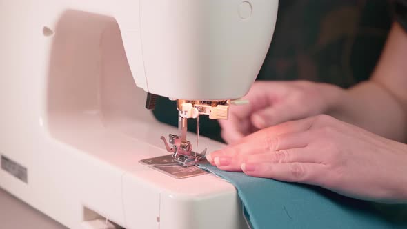 Sewing process. Sewing machine leg and woman hands close-up. Selective focus.