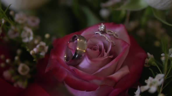 Close up of bride and groom wedding rings placed on a bouquet of beautiful flowers, slow motion shot
