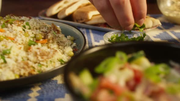 Sprinkling Greenery on Couscous with Chicken on Table Closeup