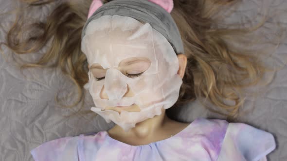 Teen Girl Applying Moisturizing Face Mask. Child Kid Take Care of Skin with Cosmetic Facial Mask