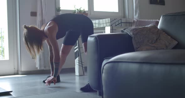 Young Tattooed Woman Warming Up Doing Stretching Before Fitness Sport Workout at Home