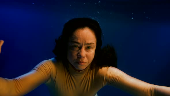 Portrait of Brunette Woman Swimming Underwater Closeup View of Face and Swaying Hair Slow Motion