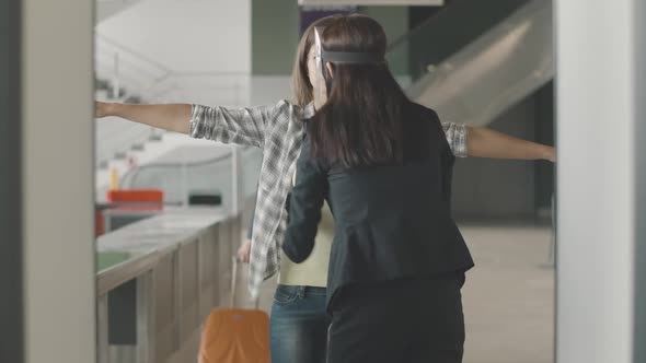 Female Employee Examining Young Woman at Security Gates in Airport While Mid-adult Man Walking with