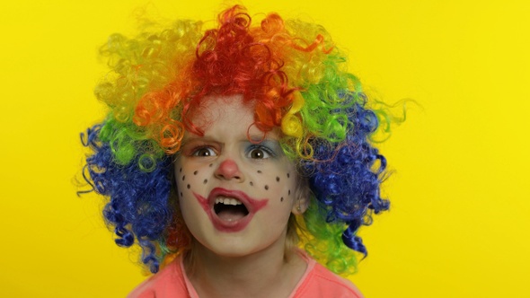 Little Child Girl Clown in Rainbow Wig Tells Something Interesting. Having Fun, Smiling. Halloween