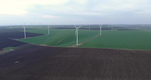 Large Wind Turbines with Rotating Blades in Field, Aerial View