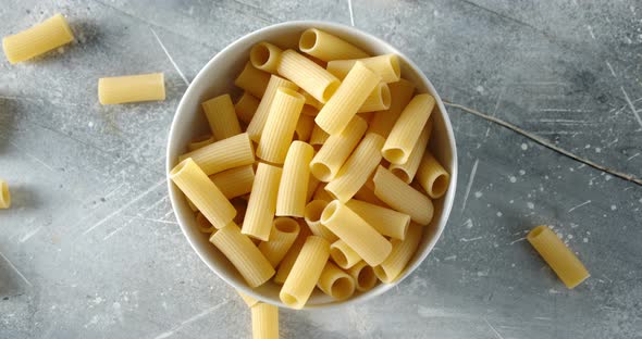 Bowl with Dry Pasta Cannelloni Rotates Slowly on the Table.