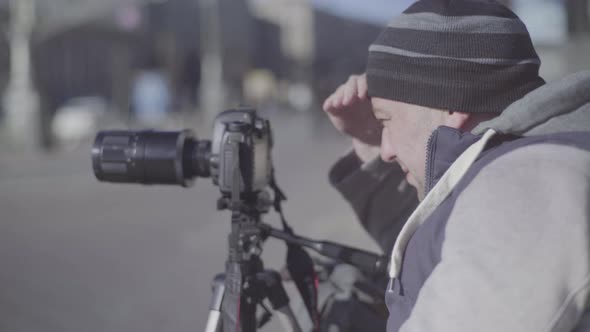 Man Male Cameraman Photographer with a Camera DSLR on a Tripod in the City Shoots Video Photo . Kyiv