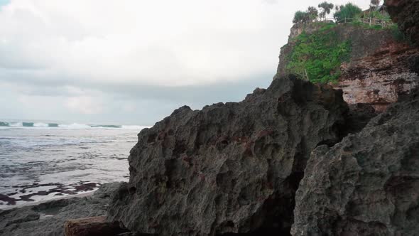 beach with big rock and cliff. the waves crashing rocks in the tropical ocean, Indonesia