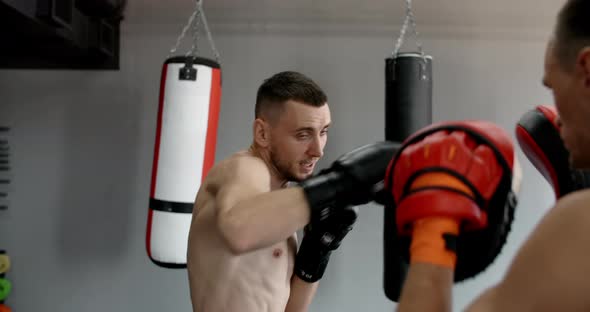 Fighter in Boxer Gloves is Practising His Strikes with Trainer in Slow Motion in the Gym Kickboxers