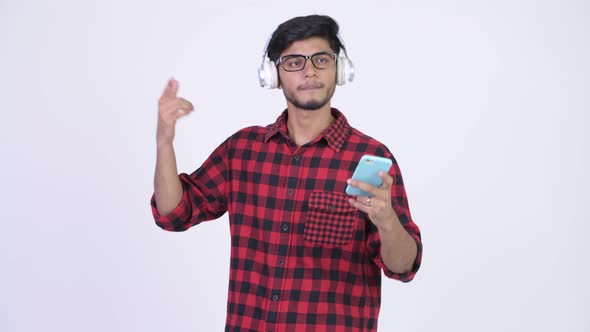 Young Happy Bearded Indian Hipster Man Listening To Music While Using Phone