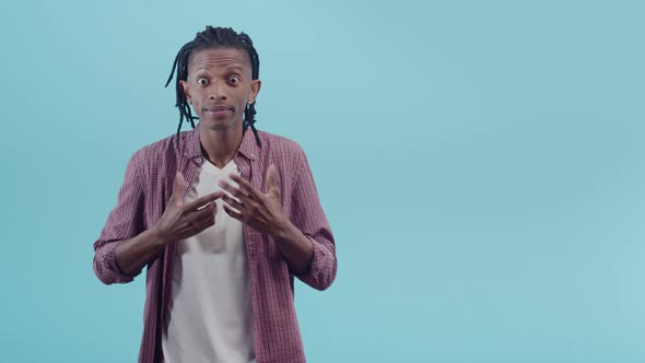 Black Man with Dreadlocks Points at Himself in Surprise and Gestures with Hands Showing No Knowledge