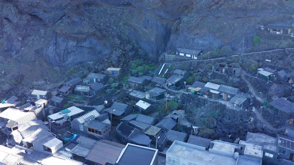 Aerial arc shot over fishing village Pozo de Las Calcosas in shadow