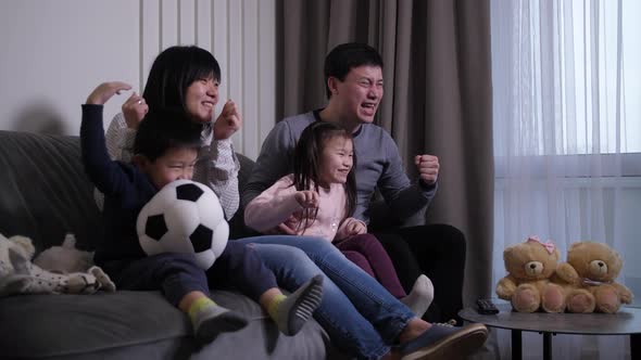 Excited Asian Family Watching Football Match on TV