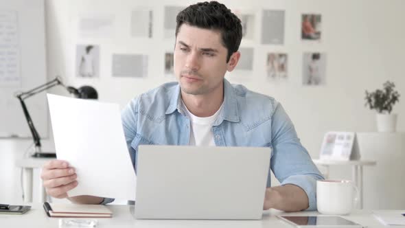 Casual Young Man Working in Office on Contract Paperwork