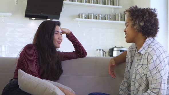 Two Girlfriends Gossiping While Sitting on the Couch