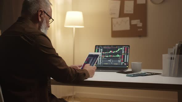 An elderly man is examining a stock market