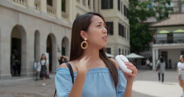 Woman feel so hot and use of hand carry fan at outdoor