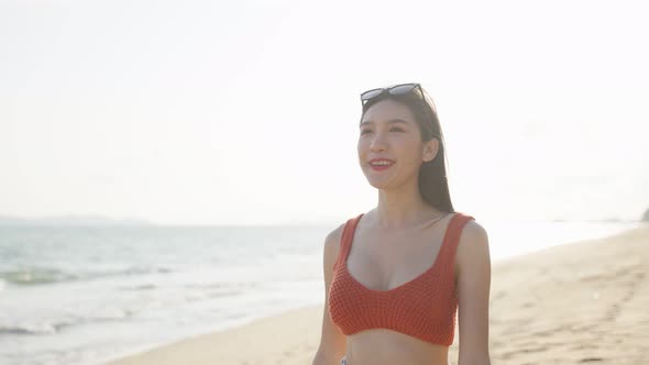 Asian young beautiful woman walking slowly on beach during summer time on holiday vacation.