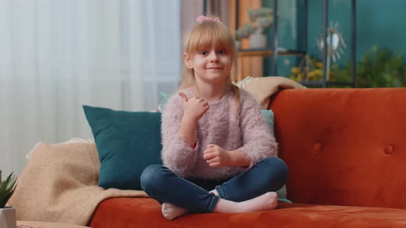 Child Girl Kid Sitting on Sofa at Home Alone Showing Thumbs Up Like Sign Positive Something Good