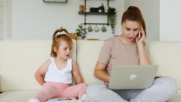 Mother Working From Home Having a Work Video Call Phone Call and Child Playing Nearby