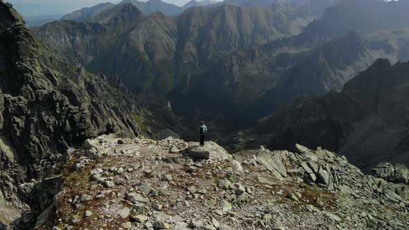 Girl Hiker Standing at the Edge of a Cliff Looking at the Valley