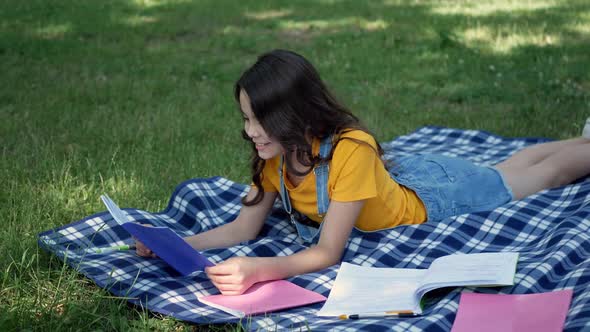 Attractive little girl lying on a blanket reading a book