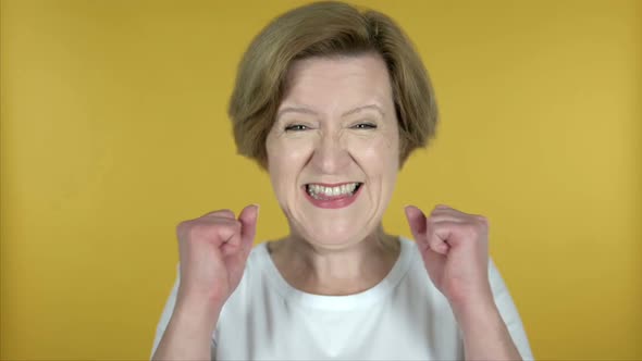 Slow Motion of Old Woman Celebrating Success Isolated on Yellow Background