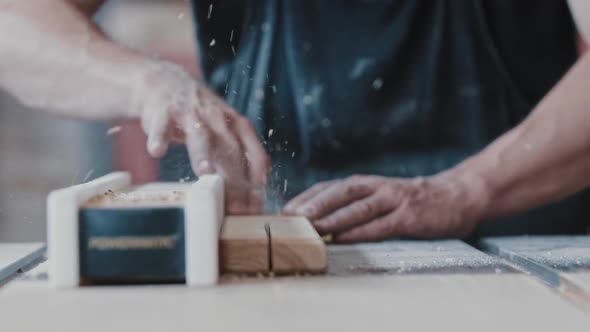 Carpentry Works  Worker Cutting the Long Wooden Detail in Two Single Parts Using an Automatic Saw