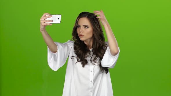 Girl of with a Smartphone in Her Hands Makes Selfie. Green Screen