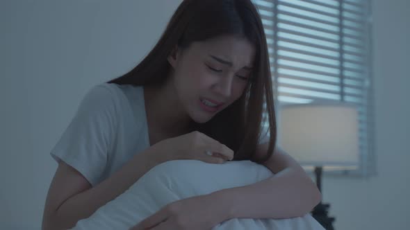 Asian beautiful depression girl crying in tears sit on bed in bedroom in dark night room at home.