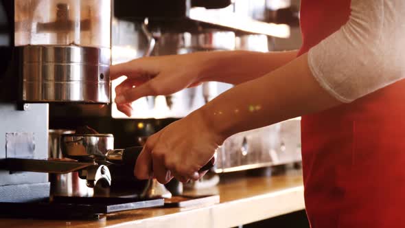 Mid section of waitress holding portafilter filled with ground coffee